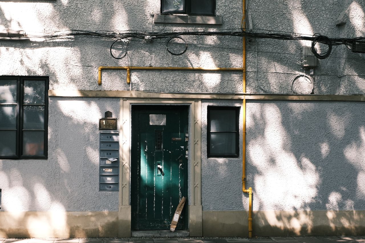 exterior wall with green door shadows and urban elements including pip