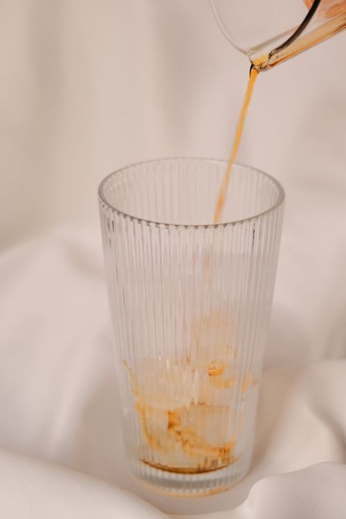 Free A vertical shot of iced coffee being poured into a glass on a white background. Stock Photo