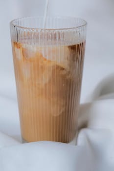 Vertical shot of a delicious iced latte with milk swirling in a glass, perfect for coffee lovers.