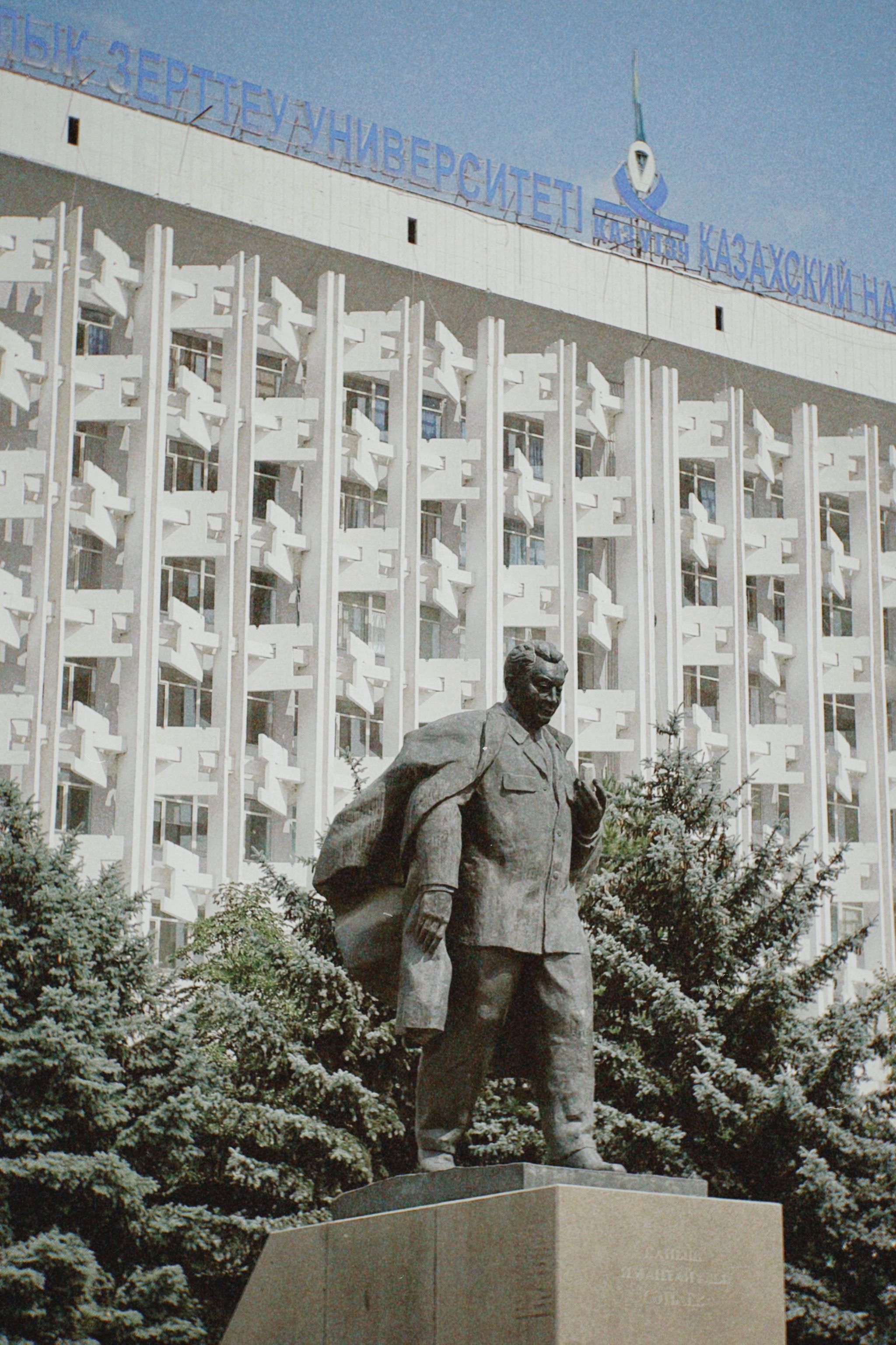 Bronze statue in front of Satbayev University's architectural facade in Almaty, Kazakhstan.