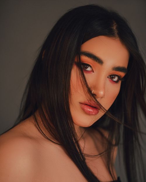 Free Close-up portrait of a young woman with striking makeup and dark hair in a studio setting. Stock Photo