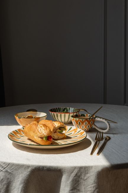 A sophisticated breakfast setup featuring a croissant on patterned crockery in moody lighting.