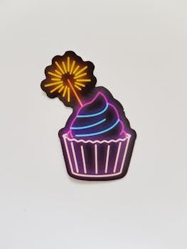 Vibrant neon sign of a cupcake with a glowing sparkler, perfect for festive themes.