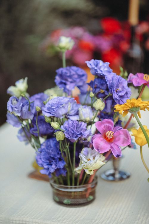 Free Vibrant purple and yellow flowers beautifully arranged in a glass vase on a table. Stock Photo