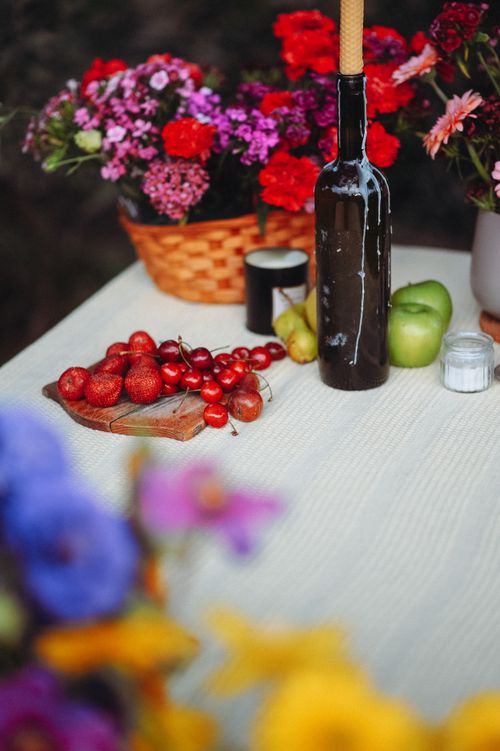 Free A vibrant rustic table setup outdoors featuring fruits, flowers, and a bottle. Stock Photo