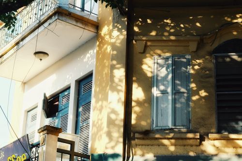 Free A sunlit urban building facade showcasing windows, a balcony, and intriguing shadows. Stock Photo