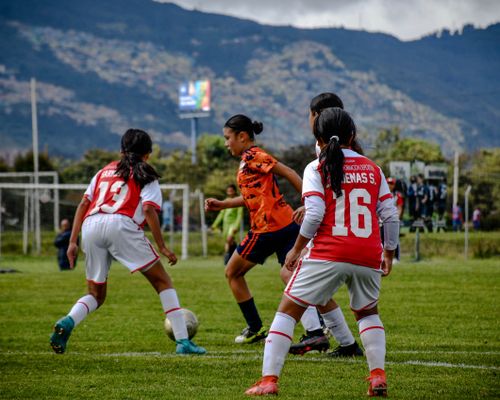 Free Young athletes engaged in a soccer match on a lush field with mountains in the background. Stock Photo