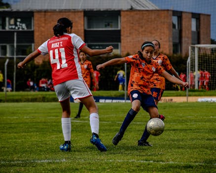 A dynamic soccer match between girls' teams in colorful sportswear on a grassy field.