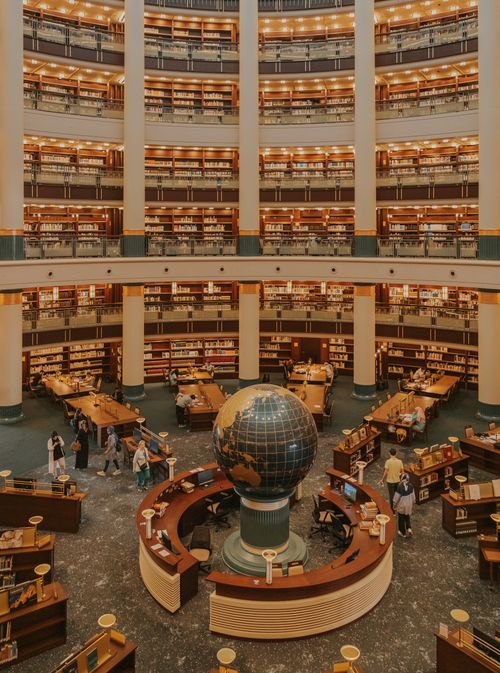 Free Explore a grand library interior featuring a large globe centerpiece and multiple levels of books. Stock Photo