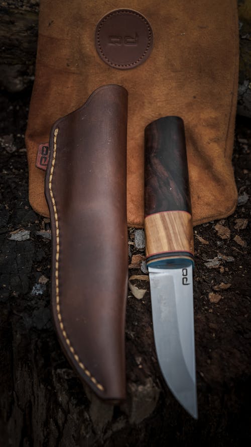 Close-up of a Sharp Knife and a Leather Case Lying on a Tree Stump 