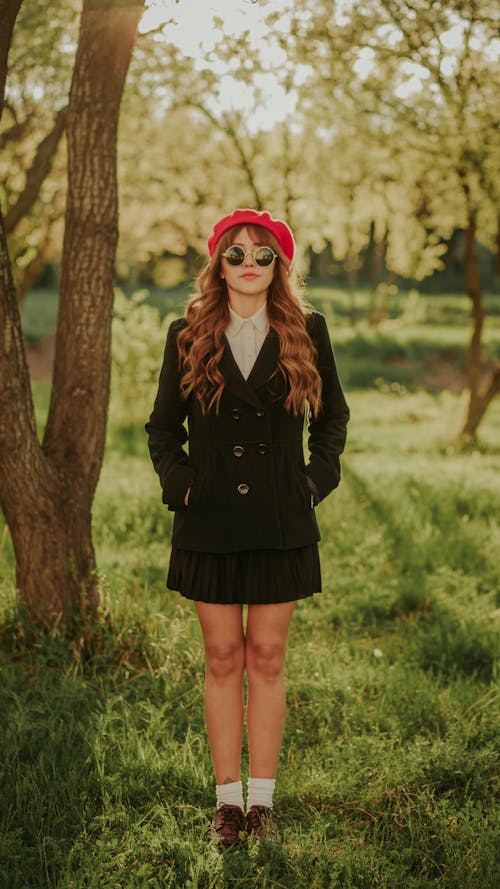 Young Long Haired Woman in Dark Green Pea Coat, Pleated Mini Skirt and Red Beret