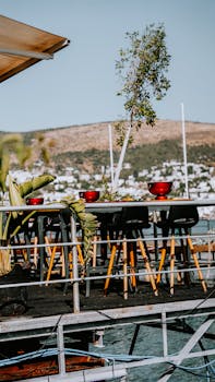 Outdoor cafe with tables and chairs by the sea and scenic mountain backdrop