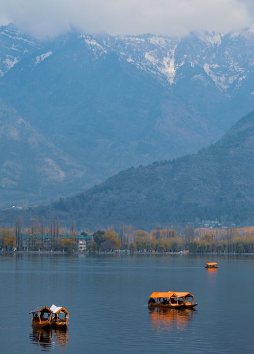 Free Serene lake with wooden boats framed by majestic snow-capped mountains. Stock Photo