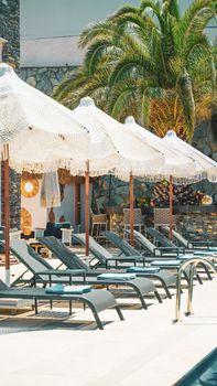 A vibrant summer scene featuring sun loungers and parasols by an outdoor pool.