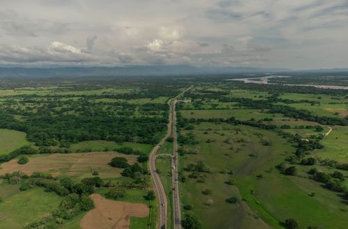 Free A scenic aerial view of a rural highway cutting through lush farmland and green fields. Stock Photo