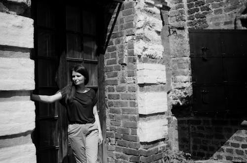 Woman Standing in Front of Brick Building in Black and White