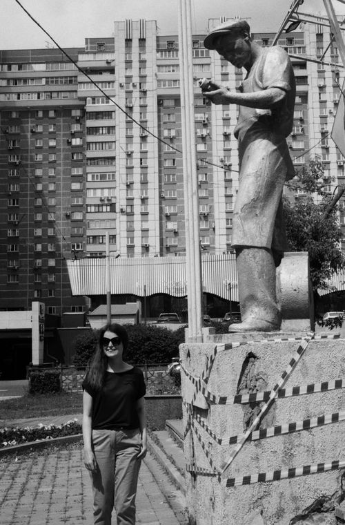 Free Black and white photo of a woman beside a statue in a city setting. Stock Photo