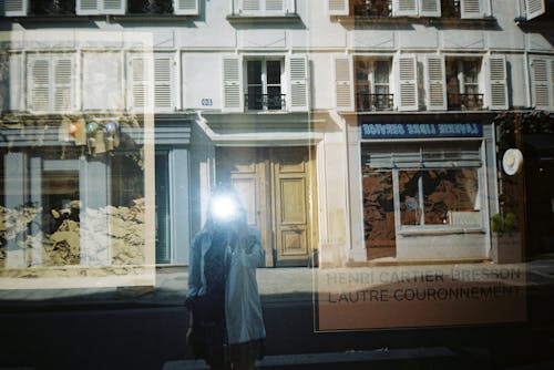 Woman Taking a Picture with a Flag in a Window of a Building in City 