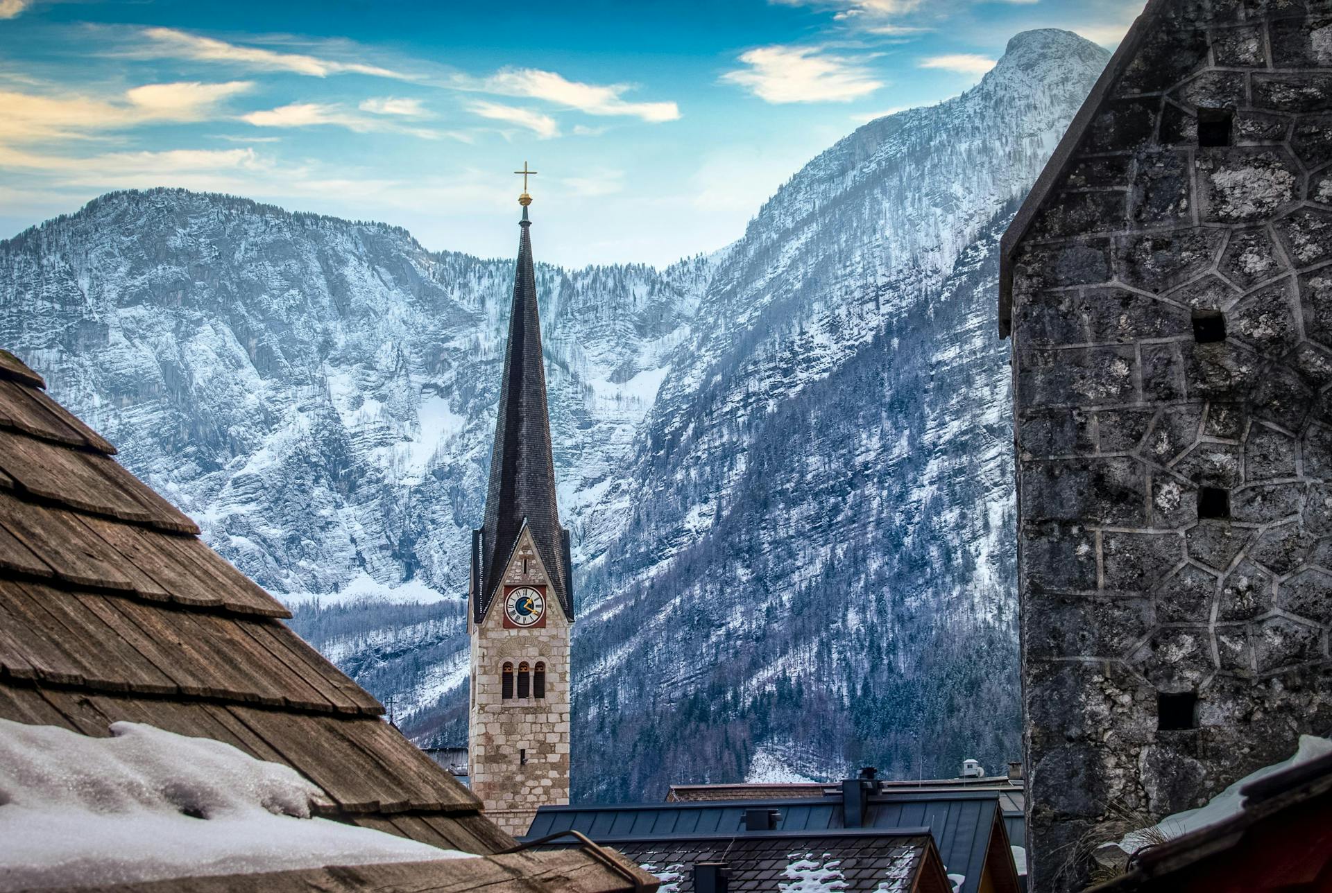 View of a church tower amidst snowy mountains in Sankt Wolfgang, Austria, showcasing winter beauty.