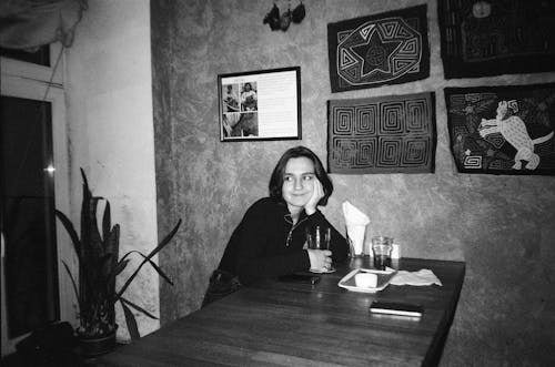 Woman Sitting by Table with Handmade Decorations on Wall over