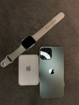 Flat lay of smartwatch, smartphone, and wireless charger on a gray background.