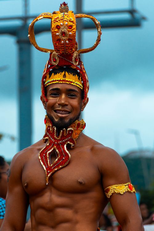 Free Portrait of a topless man smiling in a vibrant tribal costume and crown outdoors. Stock Photo