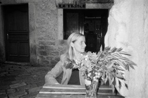 Woman Sitting by Table with Flowers