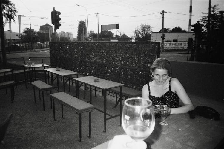 Woman Sitting Near Tables In Cafe In Town