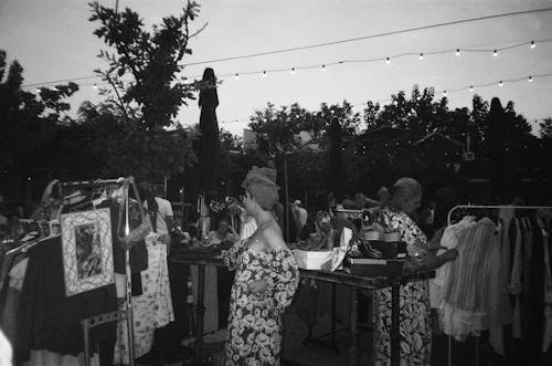 Women in Floral Patterned Dresses Choosing Clothes at an Evening Flea Market