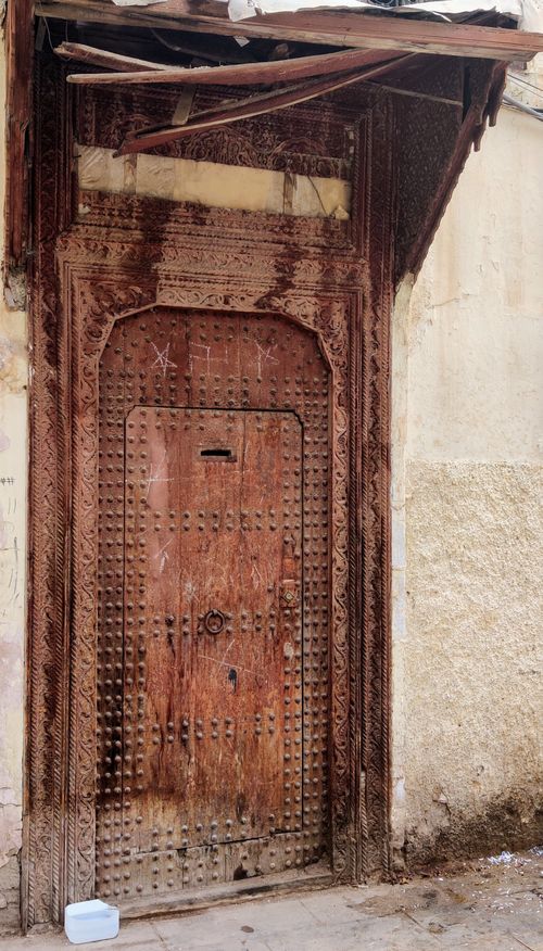 Free Explore the detailed craftsmanship of a vintage wooden door in Fès, Morocco's historic medina. Stock Photo