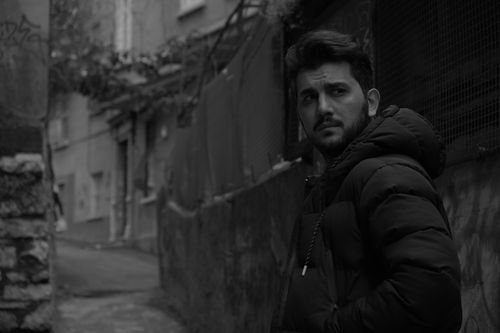 Free Black and white portrait of a man in an urban alley, wearing a jacket. Stock Photo