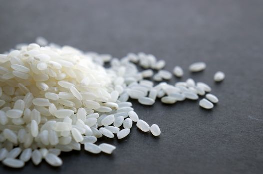 A close-up image showcasing a heap of fresh white rice grains on a dark surface.