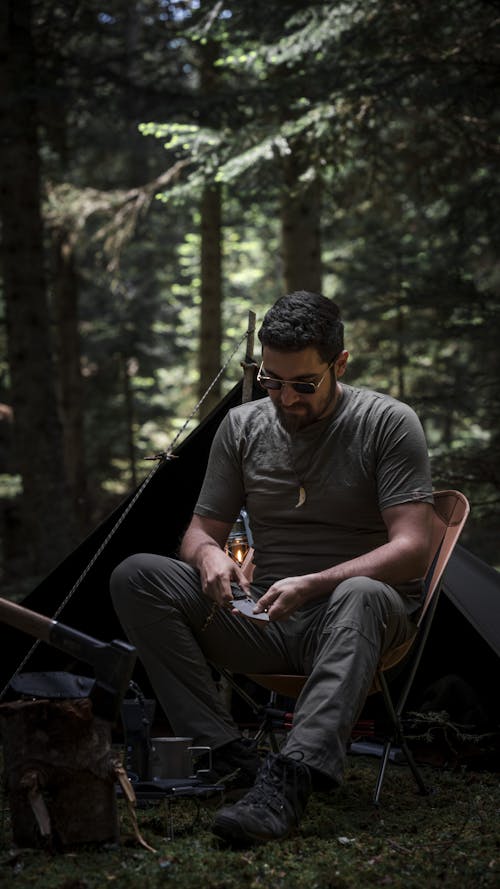 Man Sitting on Chair at Camp in Forest