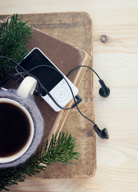 Top-down view of coffee, an MP3 player, earphones, and a stack of books, the studio cadence that fits architectural reading.