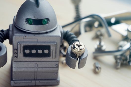 Robot đồ chơi cầm ốc vít kim loại trong bối cảnh thể hiện công nghệ và tự động hóa