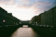 黄昏时分，运河上的建筑物和桥梁在多云的天空下呈现剪影