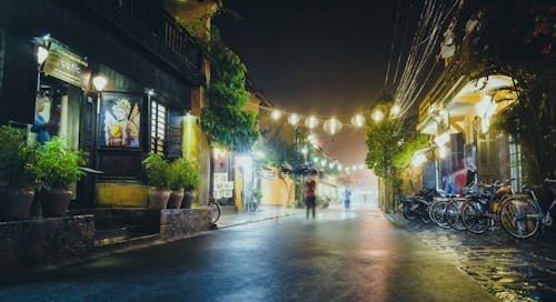 Free Person Standing on Gray Path Way Near Bicycles during Night Time Stock Photo