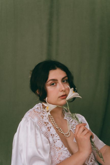 Portrait of a young woman holding lilies, showcasing elegance and beauty in a studio setting.