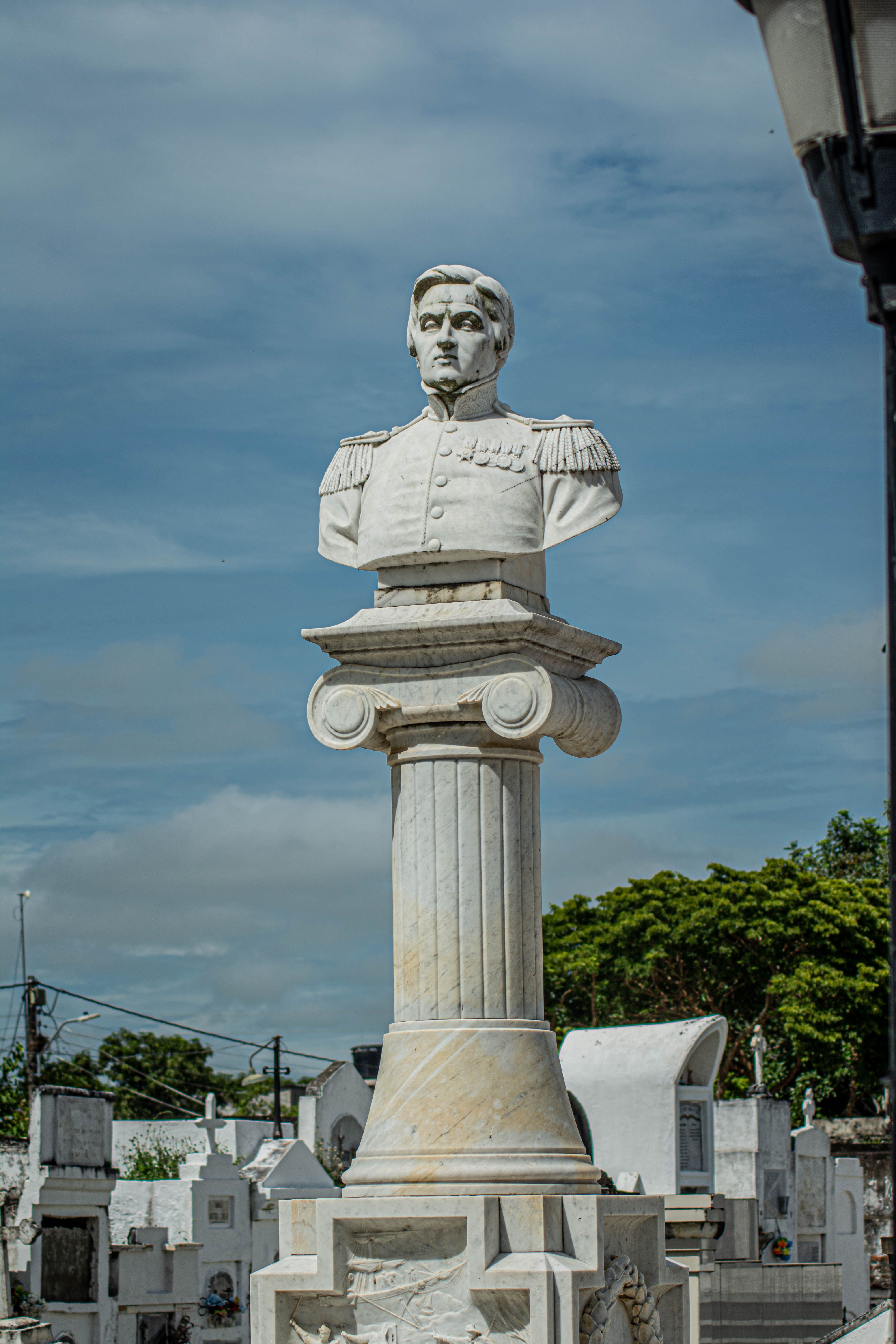 A detailed marble bust in Santa Cruz de Mompox's historic cemetery. Captured in a serene outdoor setting.
