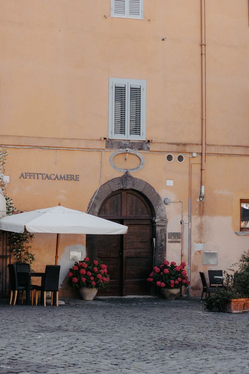 Free Cozy outdoor cafe setup in front of a historic yellow building on a cobblestone street. Stock Photo