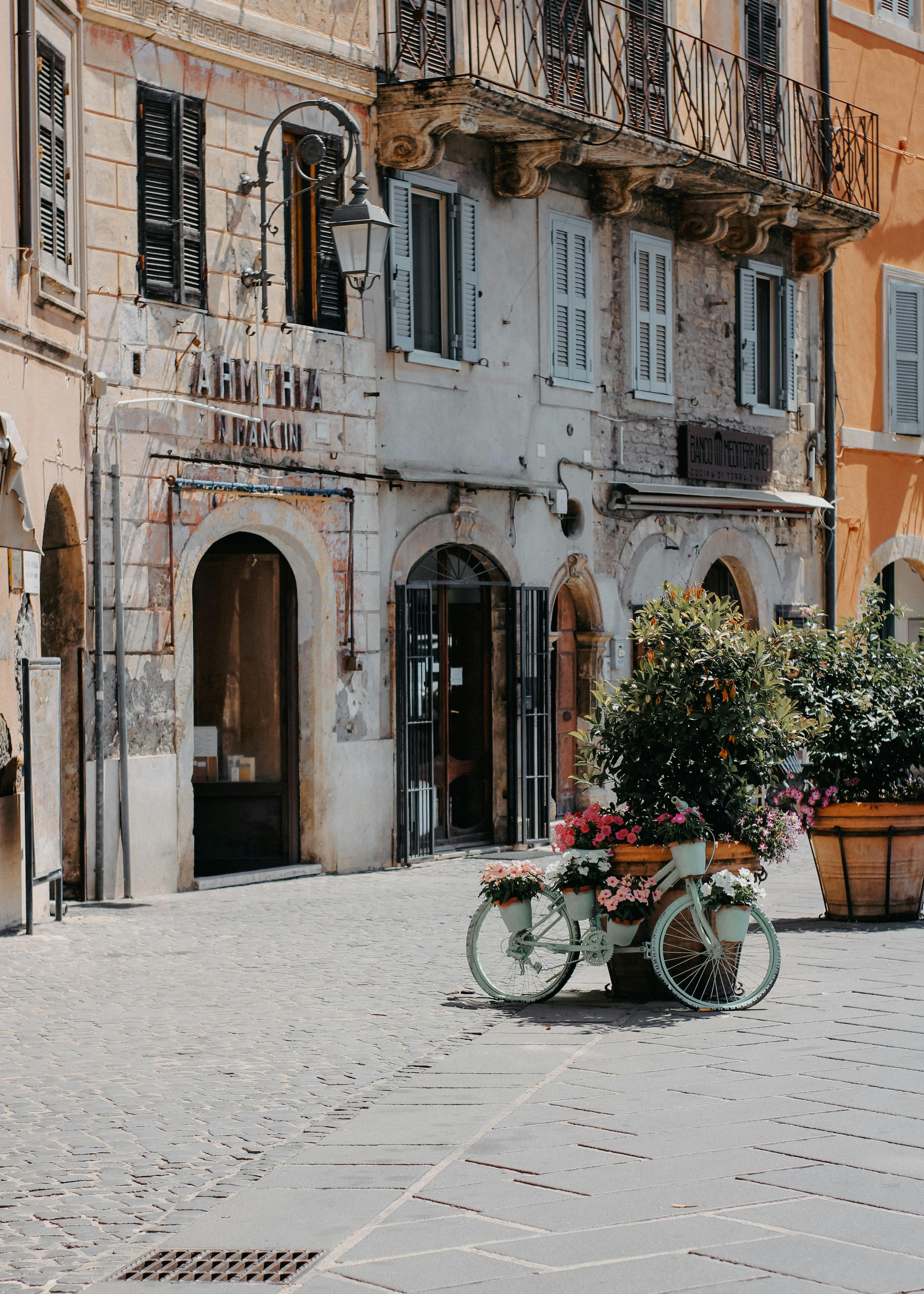 A picturesque sunlit street with cobblestones and a decorated bicycle in a European town.
