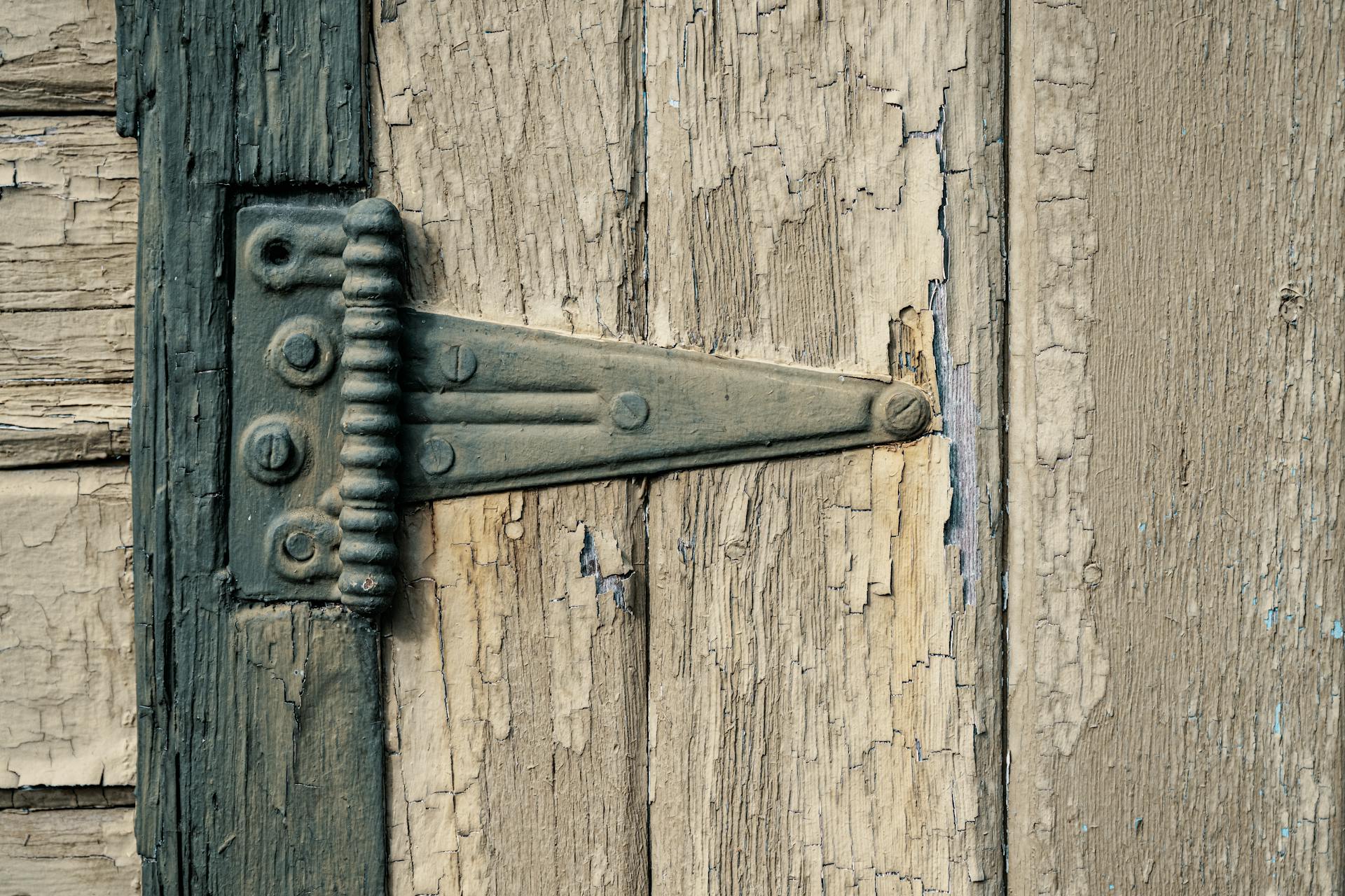 Detailed view of a rustic metal hinge on a weathered wooden door in Boise, ID.