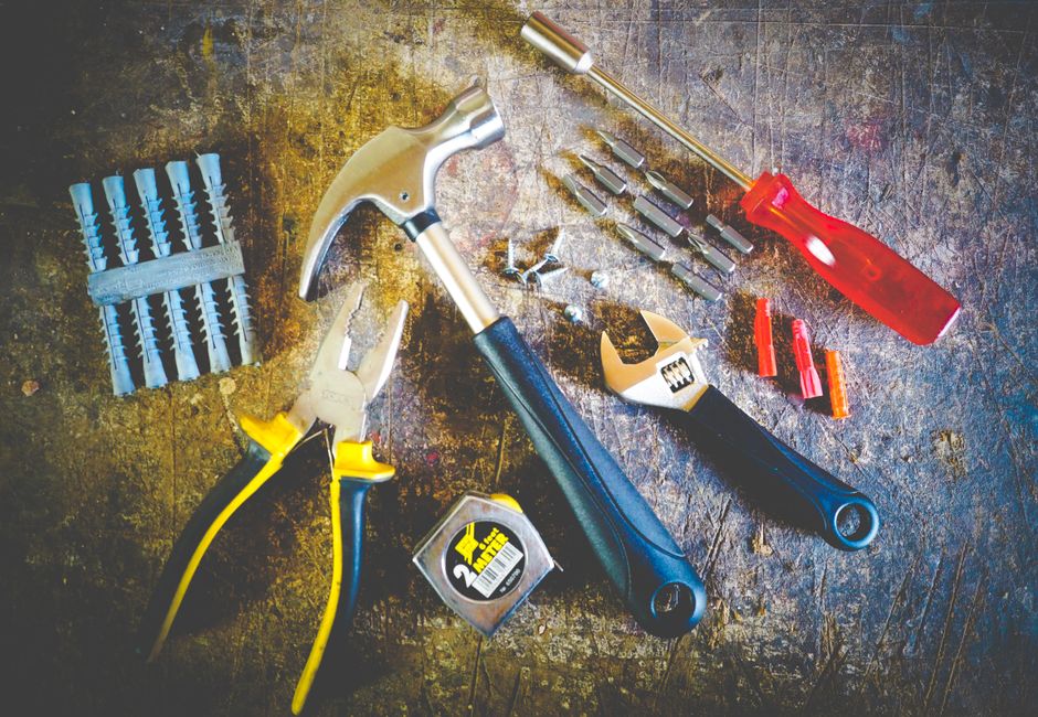 Collection of hand tools including hammer, screwdriver, and pliers in a workshop setting.