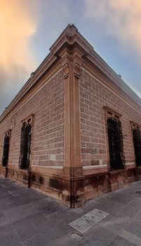 Stunning corner view of a historic brick building in San Luis Potosí, showcasing its architectural details at sunset.