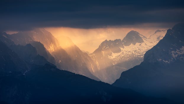 Sunset illuminates the majestic Alpine mountains under dramatic skies.
