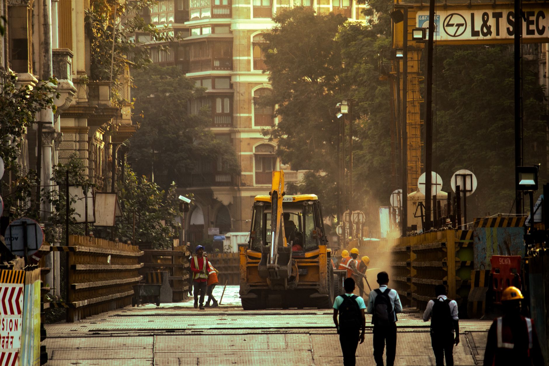 View of an active construction site with workers and machinery in Mumbai street scene.