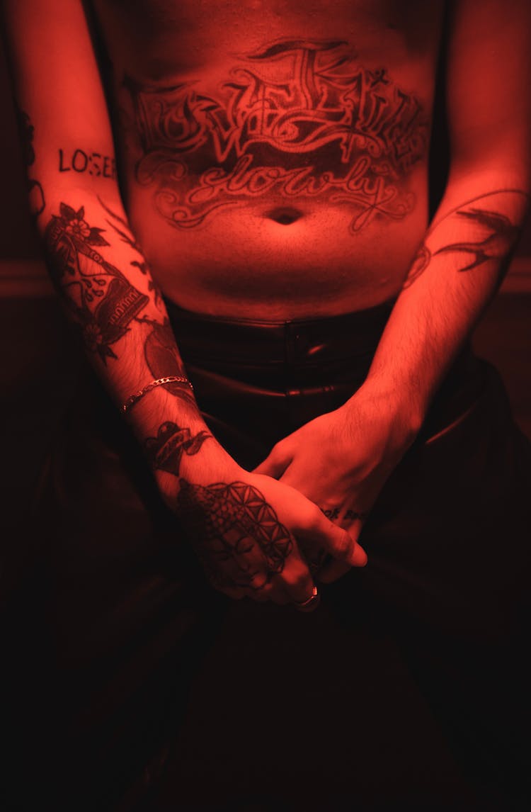 Shirtless Man With A Tattoo On His Stomach Illuminated By Red Light