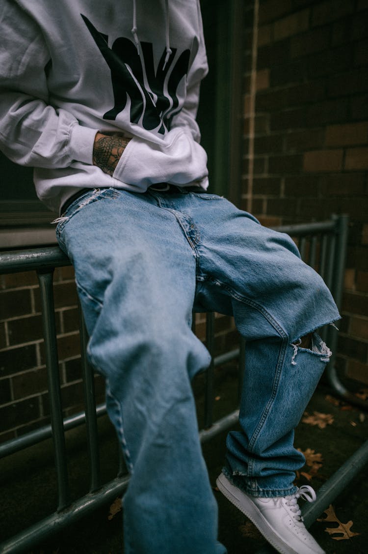 Jeans Of Man Sitting On Railing