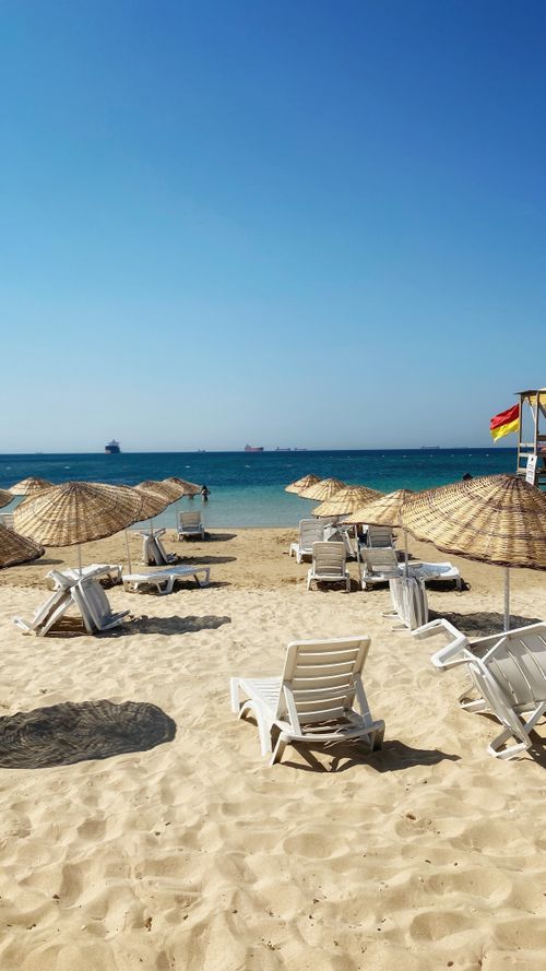 Free Relaxing beach view with sunbeds and umbrellas on a sunny day in Çanakkale, Türkiye. Stock Photo