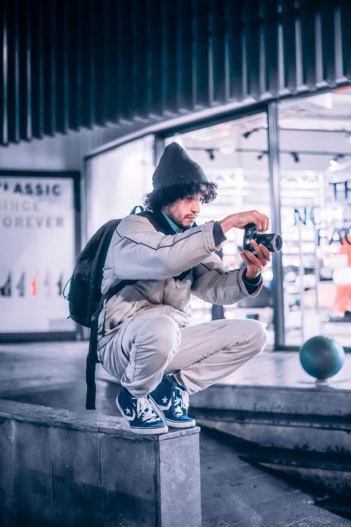 Free A man in winter clothing takes photos in an urban setting, capturing the city life. Stock Photo